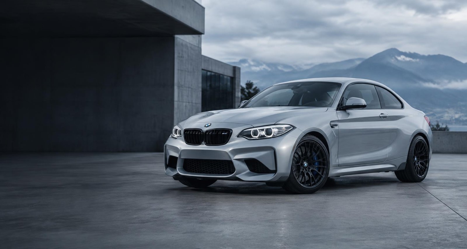 Silver BMW M2 outside a modern automotive workshop